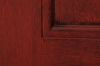 Close-up of FRAMEWELL fiberglass entry door, highlighting realistic reddish-brown wood grain stain and embossed panel detail.