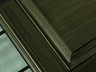 Close-up of FRAMEWELL fiberglass entry door with dark bronze brush-stained finish, embossed panel, and frosted glass.